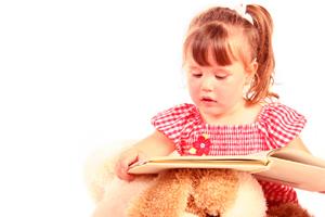 Image of a preschool girl trying to read a book