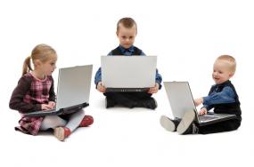 Iage of three young children using laptops