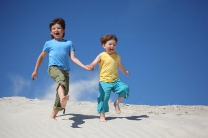 Kids holding hands while running on the beach