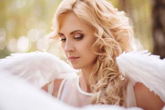 Girl spreading angel wings while standing in magical forest