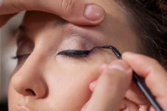 makeup artist applied eyelinear on the eye of the client