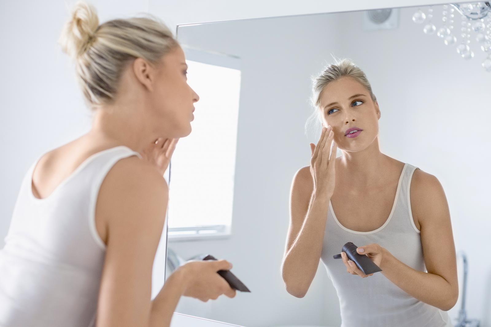 Beautiful young woman applying foundation