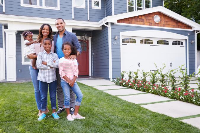 Happy family standing outside house