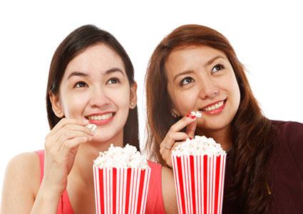 Two girls eating popcorn at the movies