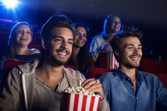happy moviegoers eating popcorn in cinema