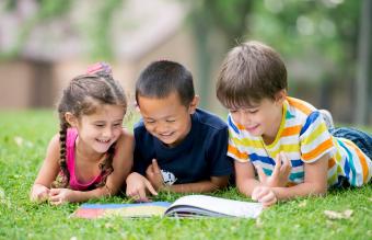 Niños leyendo un libro en el parque