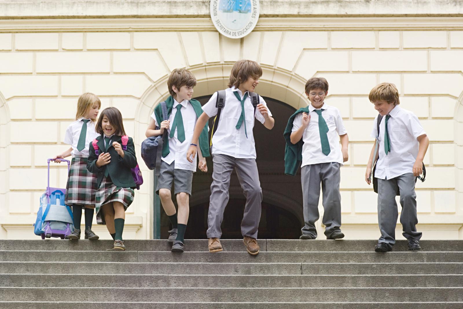 Niños en uniforme saliendo de la escuela