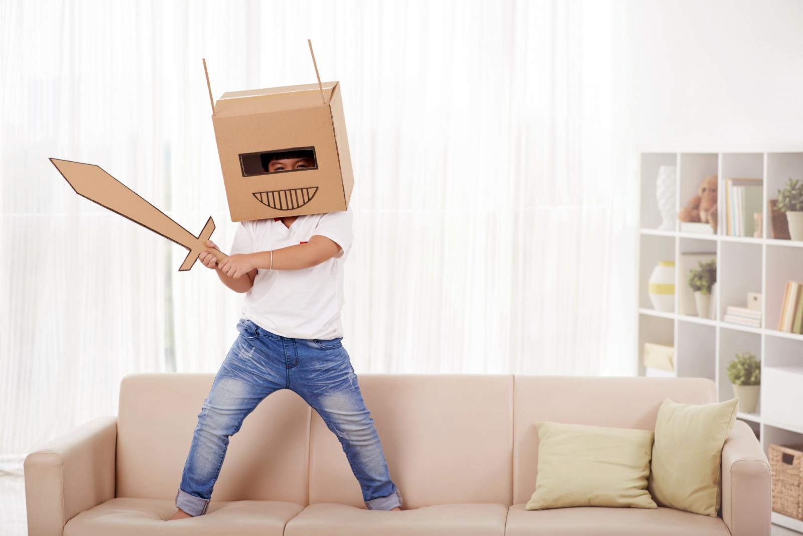 Niño jugando con cajas de cartón usando su imaginación