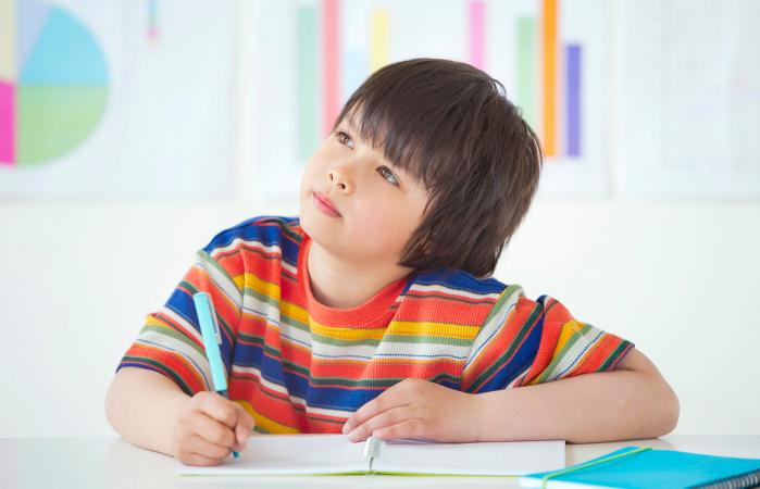 Niño sentado escribiendo en clase