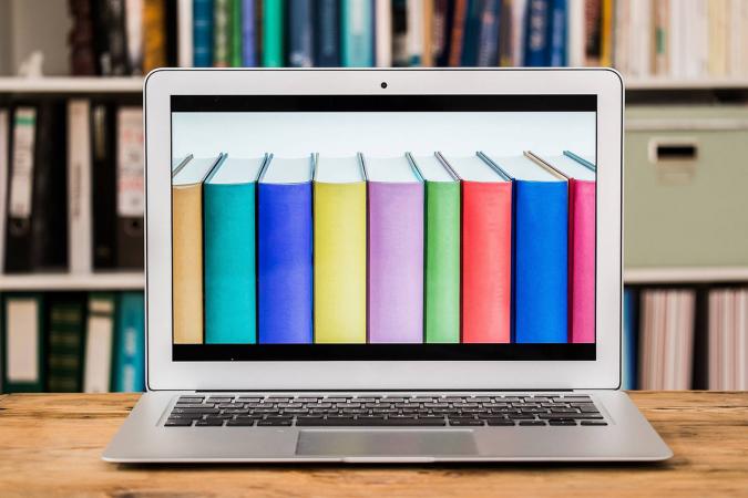 Colorful books on laptop screen at table