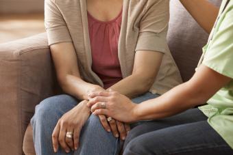 Mother and daughter holding hands on sofa