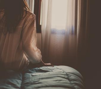 Brunette woman sitting on the edge of the bed