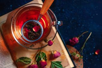 Tea strainer on an open book. Rose petals herbal tea