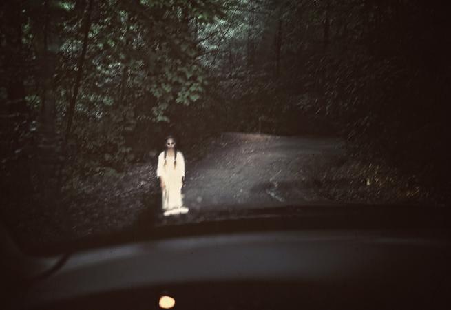 Spooky ghost standing in the middle of a dark road