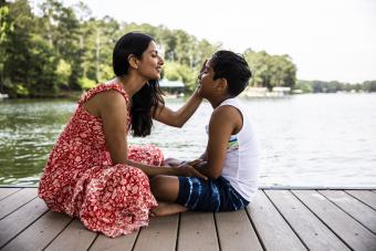 Mom wearing long dress while sitting on dock with son