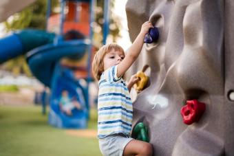 Little boy clambering up the wall on the playground