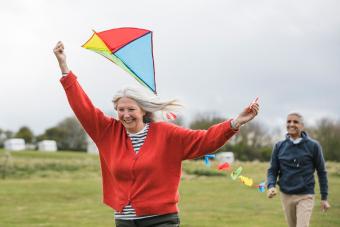 Senior friends flying a kite together in a field 