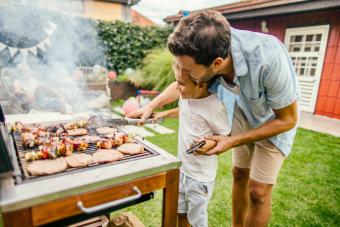 Father and son grilling meat during the barbecue party in their yard