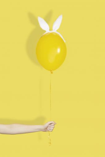 Hand holding a yellow balloon in bunny ears