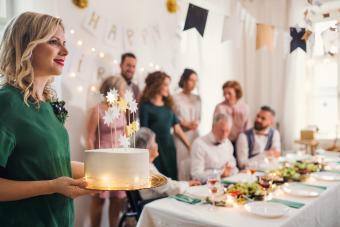 Young Woman Holding A Birthday Cake On An Indoor Party