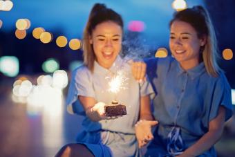 Twin sisters are celebrating their birthday with a cake and candle