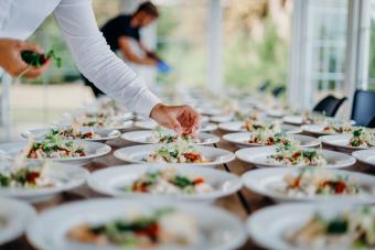 Man Serving Food In Plates On Table At A Party