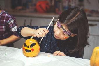 toddler decorating Halloween pumpkin