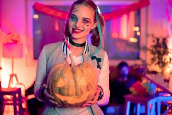 Young woman in a Halloween costume, holding Jack o' Lantern at Halloween party