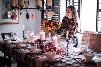 Smiling Mid Adult Woman Holding Arranging Flower Vase On Dinning Table At Home