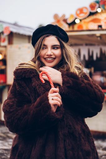 Beautiful woman in fur coat holding red and white lollipop