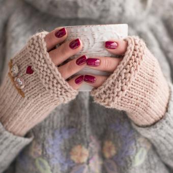 Woman wearing cozy fingerless gloves and holding a cup of hot chocolate