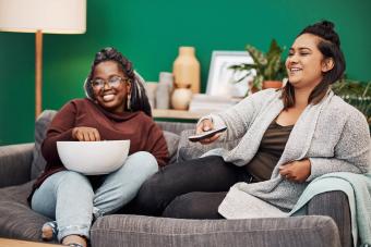 young women having popcorn and watching tv together at home