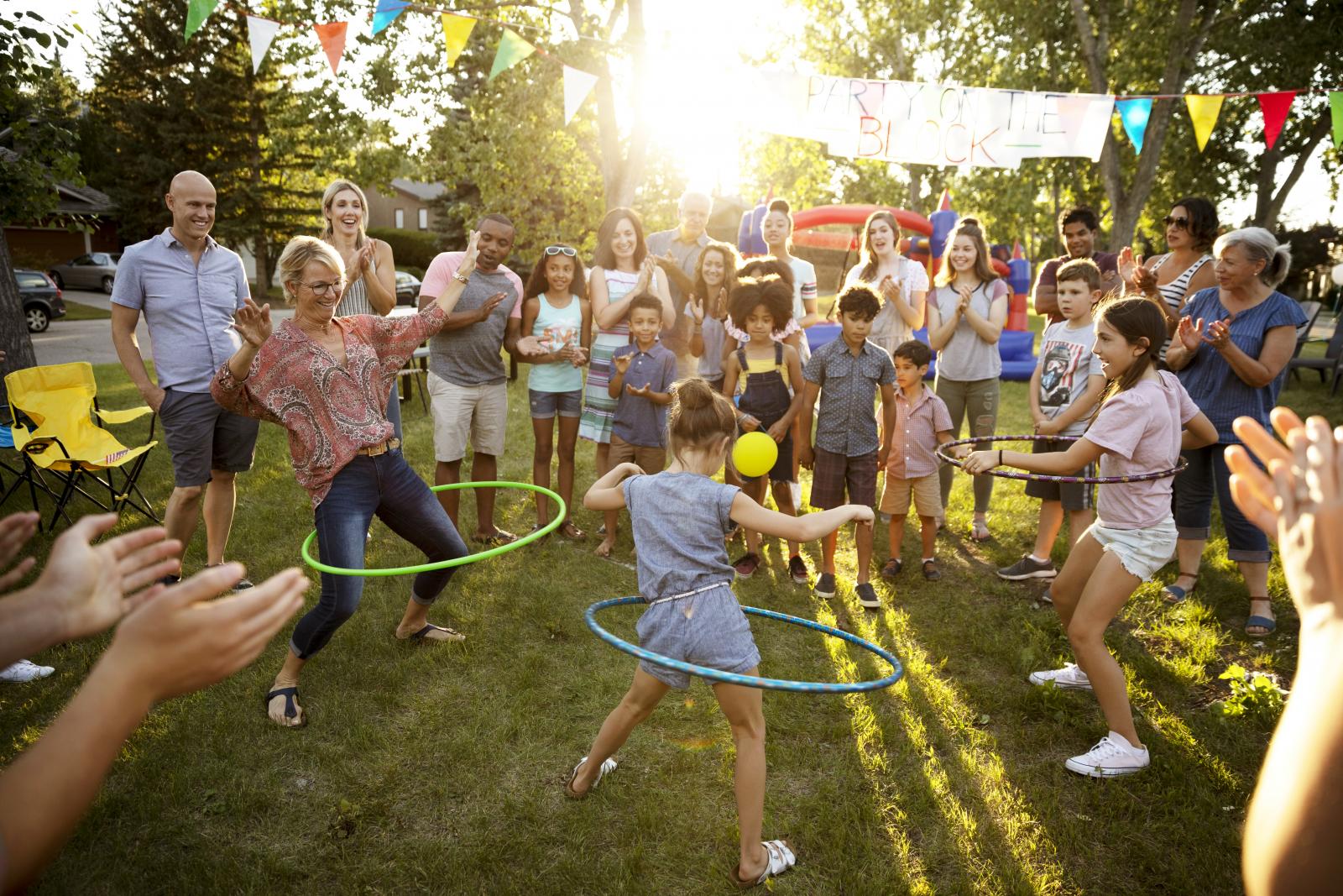 Neighbors spinning in plastic hoops at summer block party in park