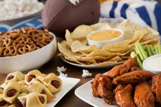 SuperBowl buffet with hot wings, pig in a blanket, nachos, pretzels, and popcorn