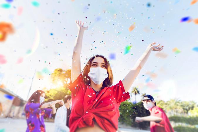 Group of teenagers celebrating at a party wearing face masks and social distancing