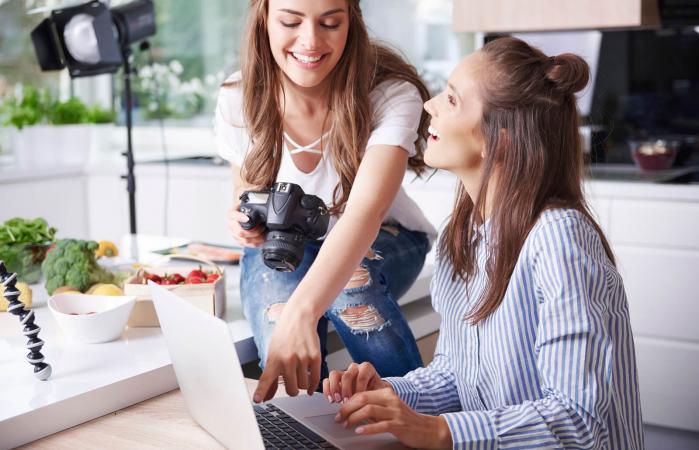 Happy women using laptop in kitchen