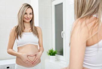 Pregnant woman looking in bathroom mirror