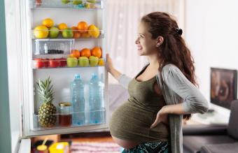 Pregnant woman standing in front of her fridge