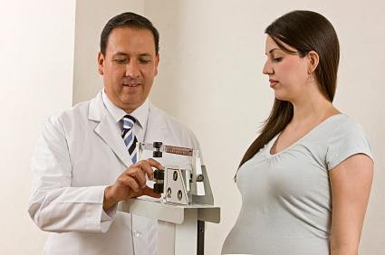 Pregnant woman being weighed by OB