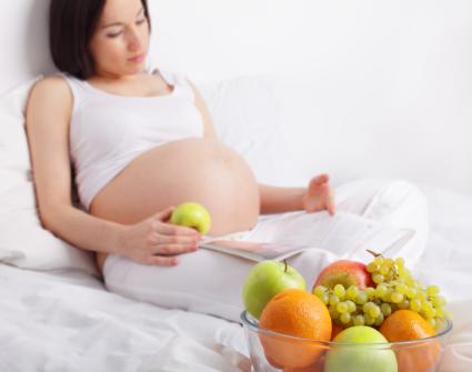Pregnant woman relaxing and eating healthy fruits