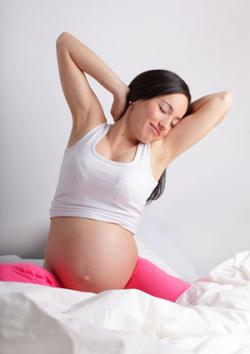 Pregnant woman stretching in bed