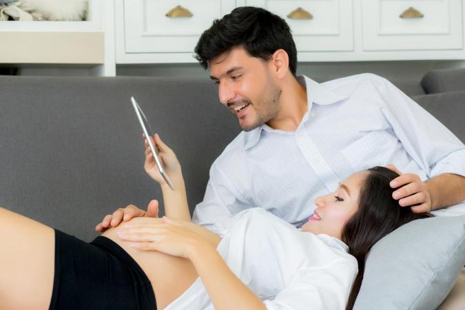 pregnant couple watching video on tablet