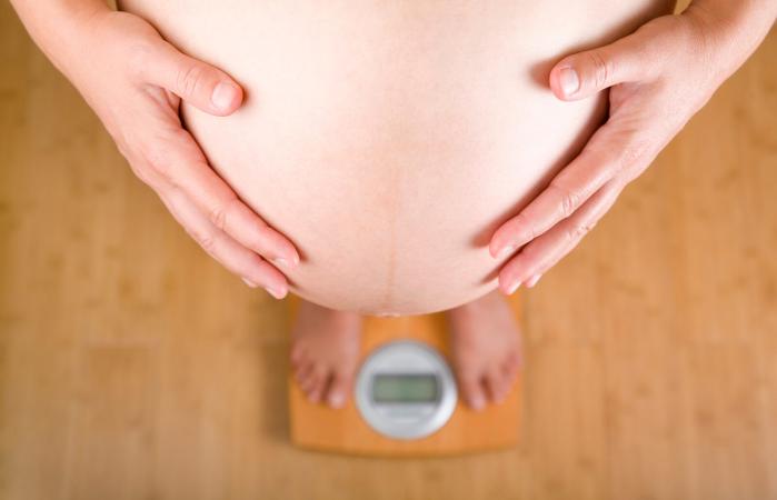 woman looking a scale over her pregnant belly