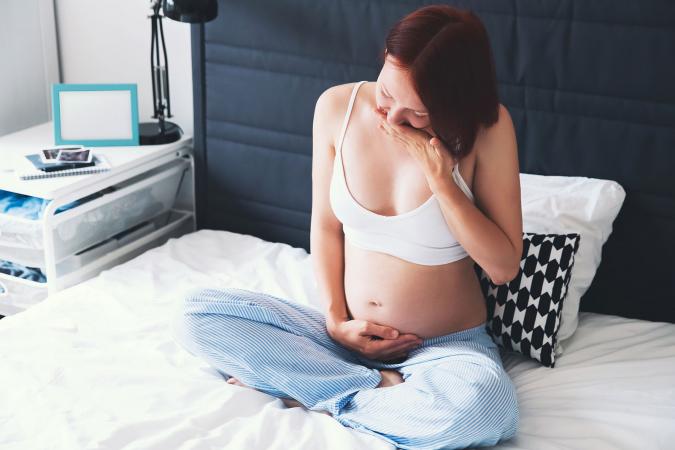 Woman on bed suffering with nausea