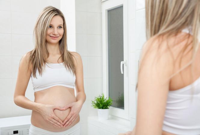 Pregnant woman looking in bathroom mirror