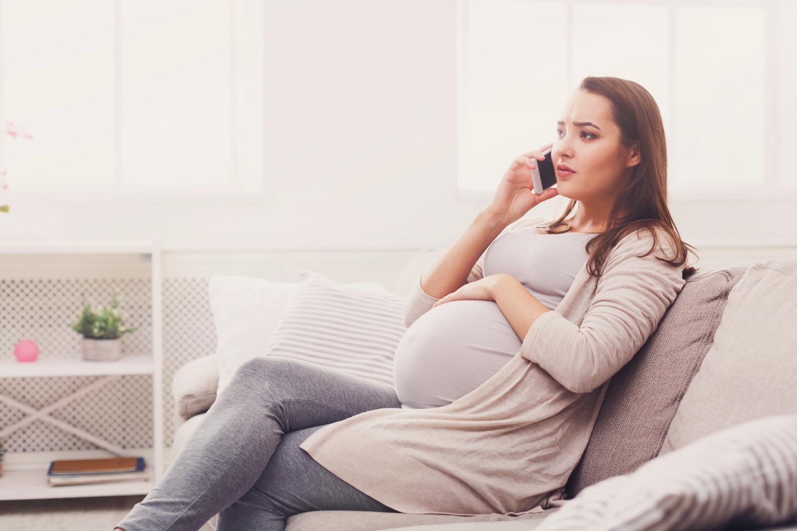 Worried pregnant woman talking on her smartphone