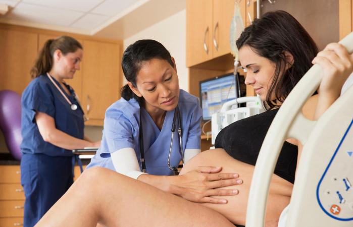 Doctor examining belly of pregnant woman