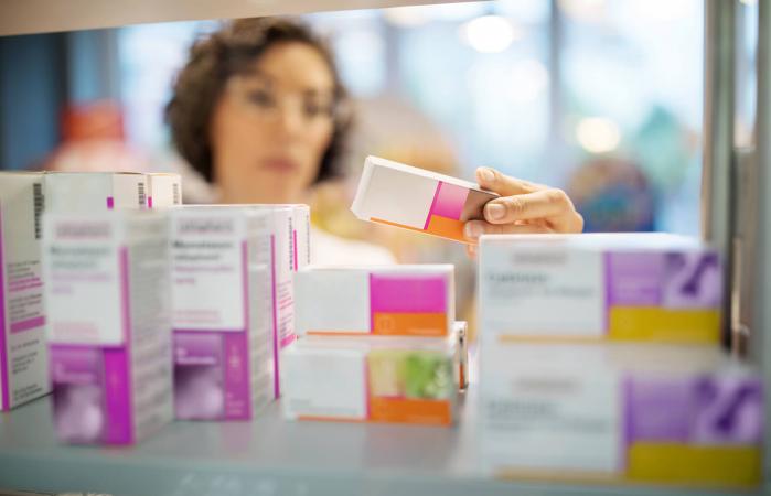 Female pharmacist checking medicines on rack