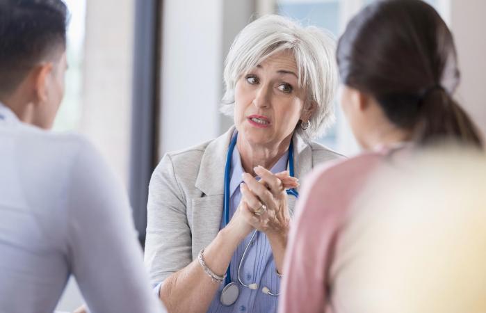 Serious doctor talks with young couple