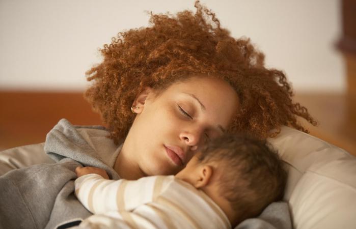 mother sleeping on sofa with baby